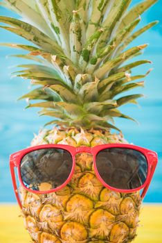 Holiday pineapple have sunglasses on blue wooden background, tropical holiday concept