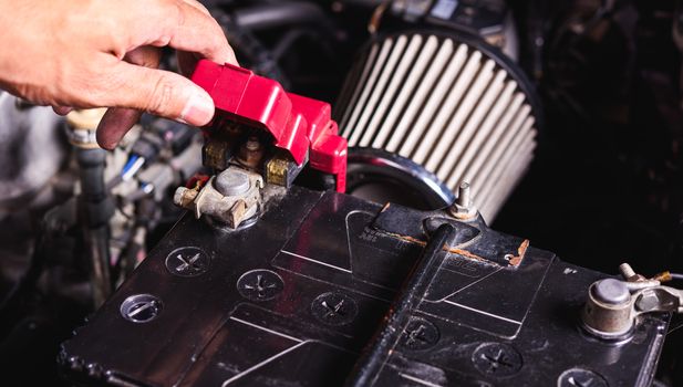 Hand of technician service check battery and turn battery screw loose in garage