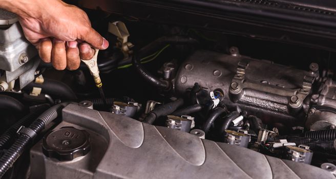 Hand of Mechanic technician service check level motor oil engine in garage