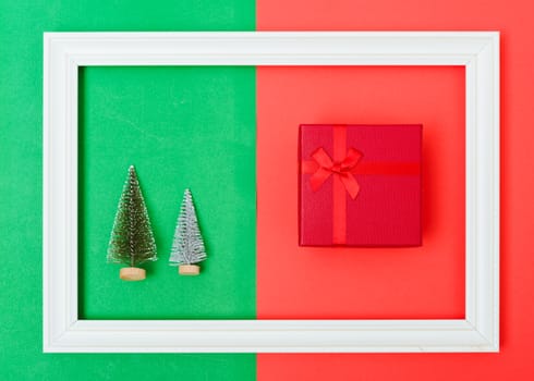 New Year, Christmas Xmas holiday composition, Top view green fir tree branch and red gift box in frame on red and green background with copy space