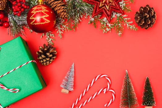 Christmas green gift box and decorations, fir tree branches on red background. Merry Christmas concept. With Copy space for text