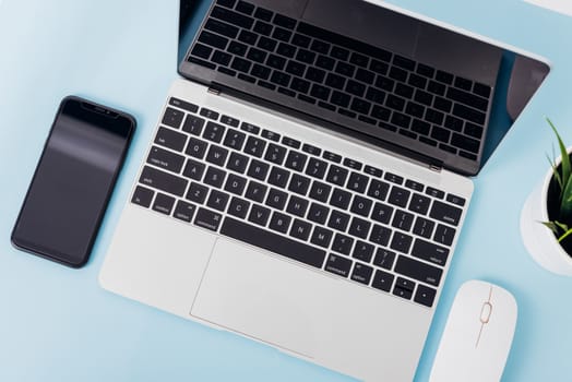 Top view of modern technology smart phone mobile and computer laptop on blue background with copy space