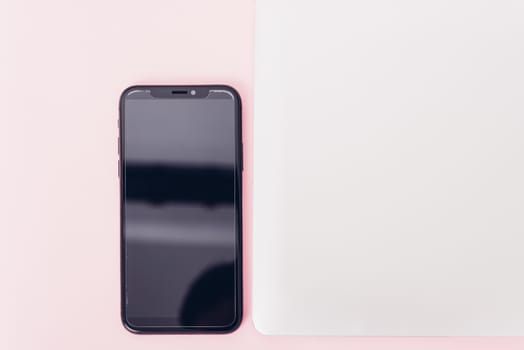 Top view of modern technology smart phone mobile and computer laptop close cover on pink background with copy space