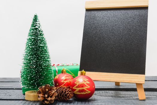 Christmas composition decorations, minimal green fir tree branches with snow and black chalkboard on white background. Merry Christmas concept. Copy space for text