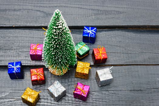Christmas composition decorations, minimal green fir tree branches with snow and gift boxs on black wooden background. Merry Christmas concept. Copy space for text
