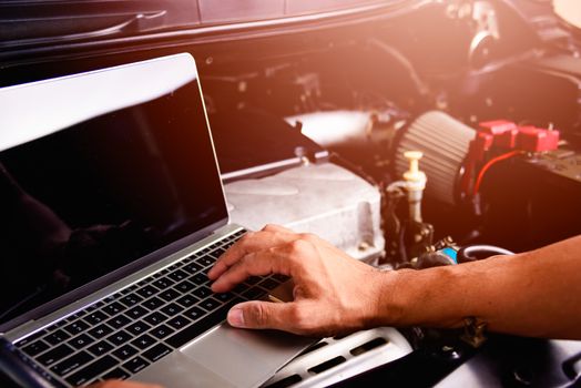 Professional car repair or maintenance mechanic engine working service with laptop computer at workshop