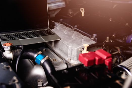 Laptop computer on car mechanic engine for service at workshop