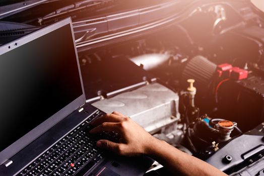 Professional car repair or maintenance mechanic engine working service with laptop computer at workshop