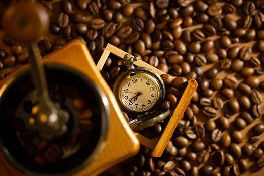 Coffee bean and pocket watch the tray of manual grinder on table. Top view and copy space. Concept of coffee time in morning.