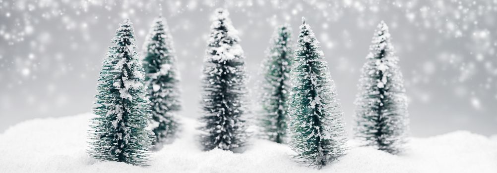 Winter wonderland with small decorative fir trees at snowfall, winter holidays concept