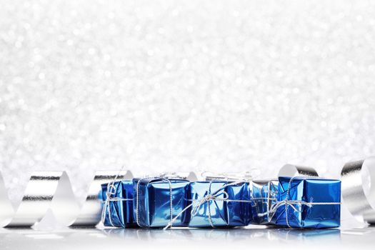 Decorative blue boxes with holiday gifts on shiny glitter background