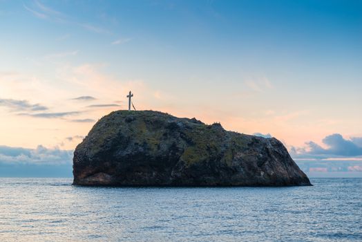 Rock with a cross on top and the sea, the dawn