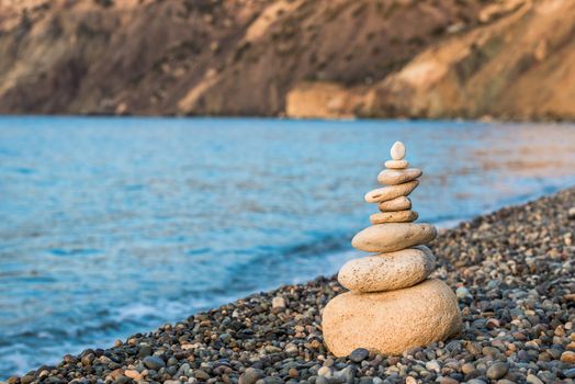 concept photo balance - close-up of a pyramid of white stones on a pebble beach