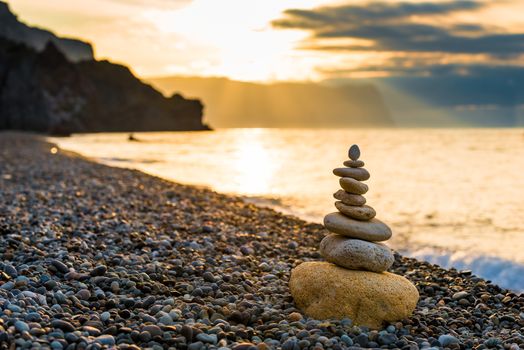 concept photo balance at dawn - close-up of a pyramid of white stones on a pebble beach