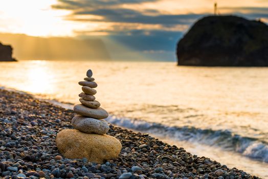 balance at dawn - close-up of a pyramid of white stones on a pebble beach