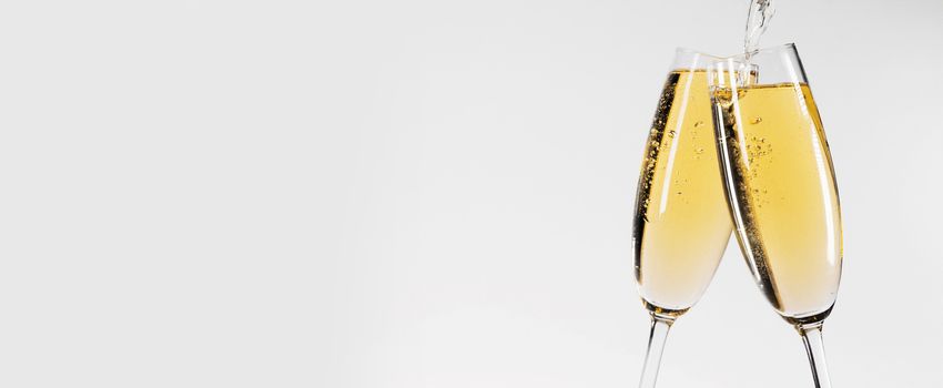 Two glasses of champagne on white background, pouring wine