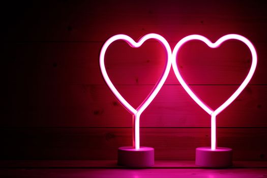 Two glowing pink neon hearts Valentines day party concept