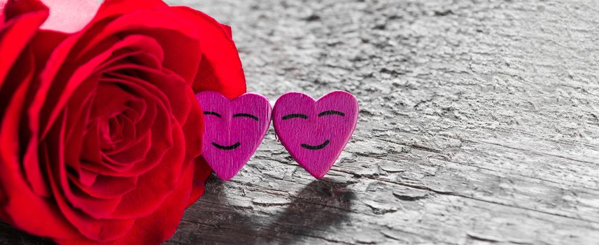 Red rose and decorative hearts over wooden background