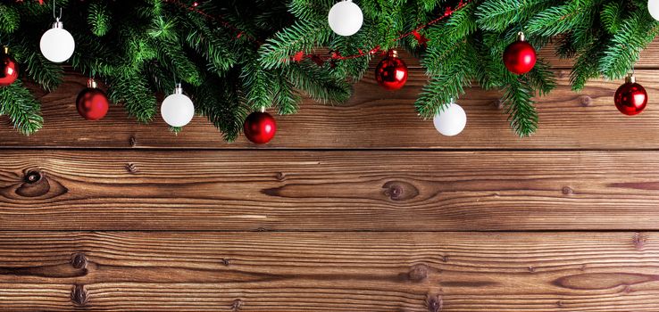 Christmas fir tree and decorative baubles on wooden background