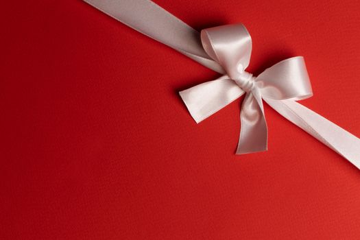 Elegant satin white ribbon bow on red background
