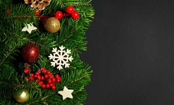 Natural fir Christmas tree border frame with decor on black, copy space for text
