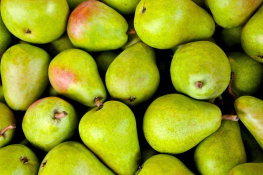 In images fresh pears with leaves in a box on wooden table, top view