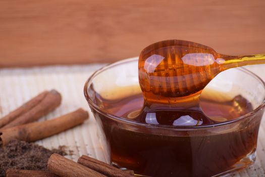 In images Golden honey with honeystick. cinnamon and anise stars on wooden table