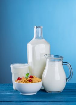 In images A glass of milk and a milk jug on plaid tablecloth.