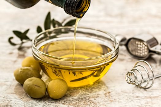 In images Olive oil and olive branch on the wooden table over nature background