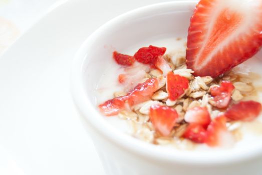 In images Fresh homemade muesli, muesli with strawberries in a plate on a blue background, selective focus