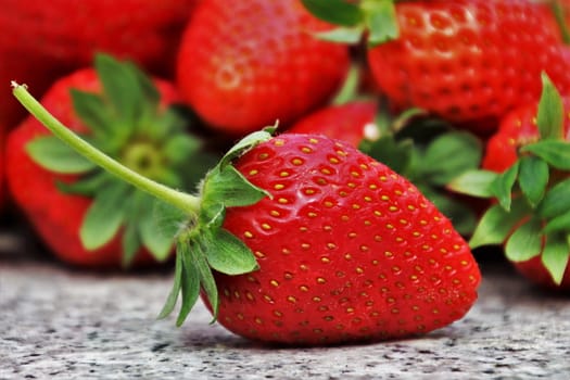 In images Ripe strawberries in saucer on wooden table on blurred background