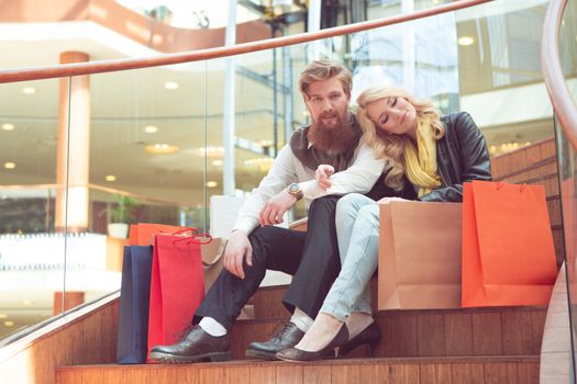 Handsome couple sitting on stairs after shopping at the mall