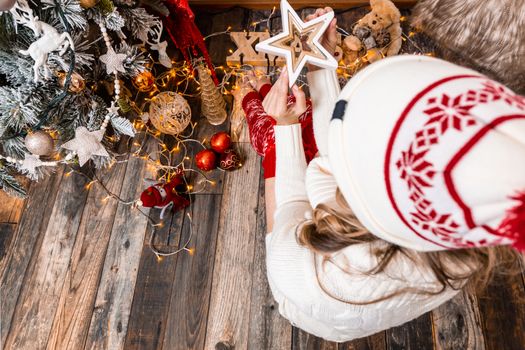 A female holds a Christmas star sitting by the tree at Christmas time