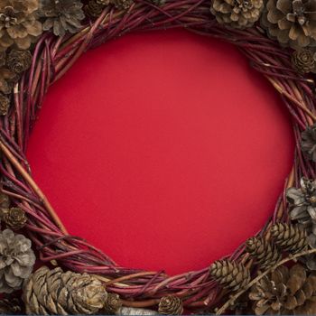 Christmas natural eco style spruce pine cone wreath over red background flat lay top view with copy space for text