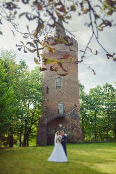 Bride and groom at a photo session in the nature. Old castle tower