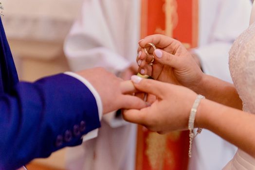 the bride and groom during the wedding ceremony put wedding rings on their fingers.