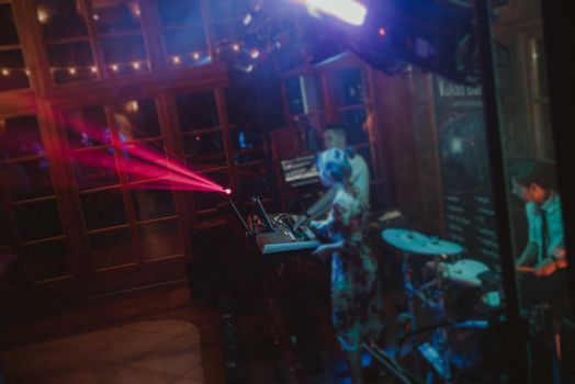 DJ plays music at wedding party. Colorful light rays.