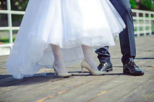 The bride shows white wedding shoes. Wedding detail. Close up