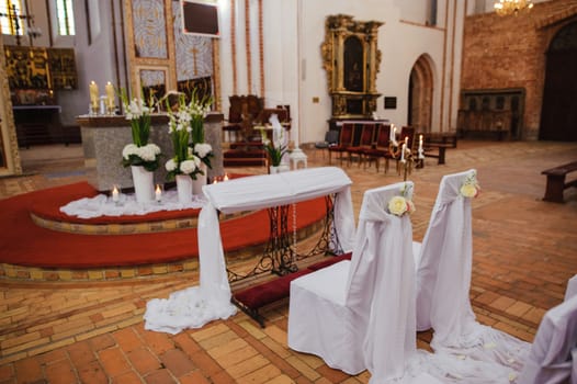 Church sanctuary before a wedding ceremony. Empty chairs for bride and groom