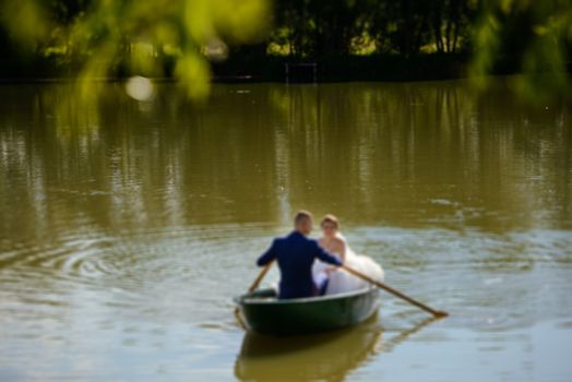 Bride and groom at a photo session in the nature. Newlyweds in the boat on the lake