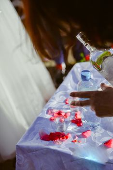 Bottle of cold vodka and wine bottle in bucket with ice and orange juice in jug on table, copy space. Alcohol bottles in ice bucket in restaurant. Wedding party