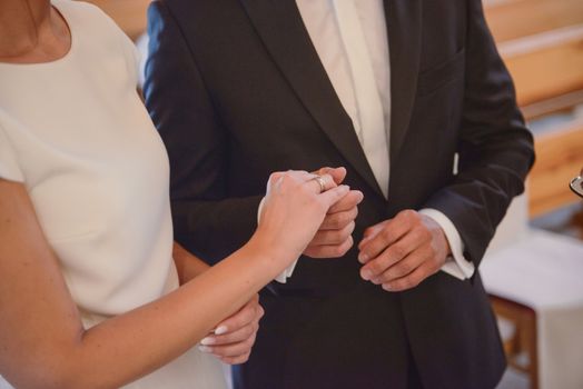 the bride and groom during the wedding ceremony put wedding rings on their fingers.