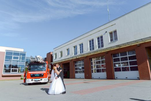 Beautiful wedding couple on outdoor photoshoot with fire truck