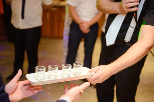 Bottle of cold vodka and wine bottle in bucket with ice and orange juice in jug on table, copy space. Alcohol bottles in ice bucket in restaurant. Wedding party