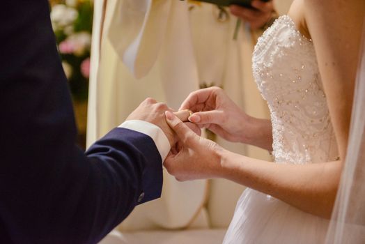 the bride and groom during the wedding ceremony put wedding rings on their fingers.
