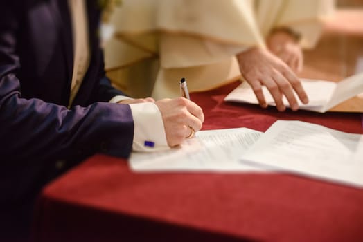 Bride and groom signing wedding contract proving their marriage.