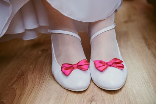 The bride shows white wedding shoes. Wedding detail. Close up