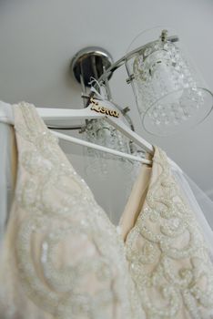Bridesmaid helping slender bride lacing her wedding white dress, buttoning on delicate lace pattern with fluffy skirt on waist. Morning bridal preparation details newlyweds. Wedding day moments, wear.