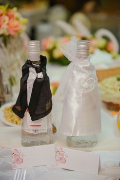Bottle of cold vodka and wine bottle in bucket with ice and orange juice in jug on table, copy space. Alcohol bottles in ice bucket in restaurant. Wedding party