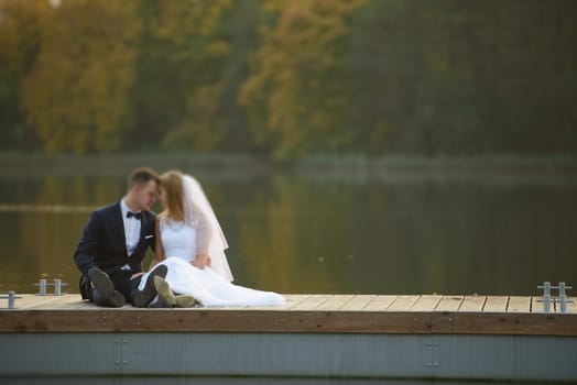 Bride and groom at a photo session in the nature. Lake and pier.
